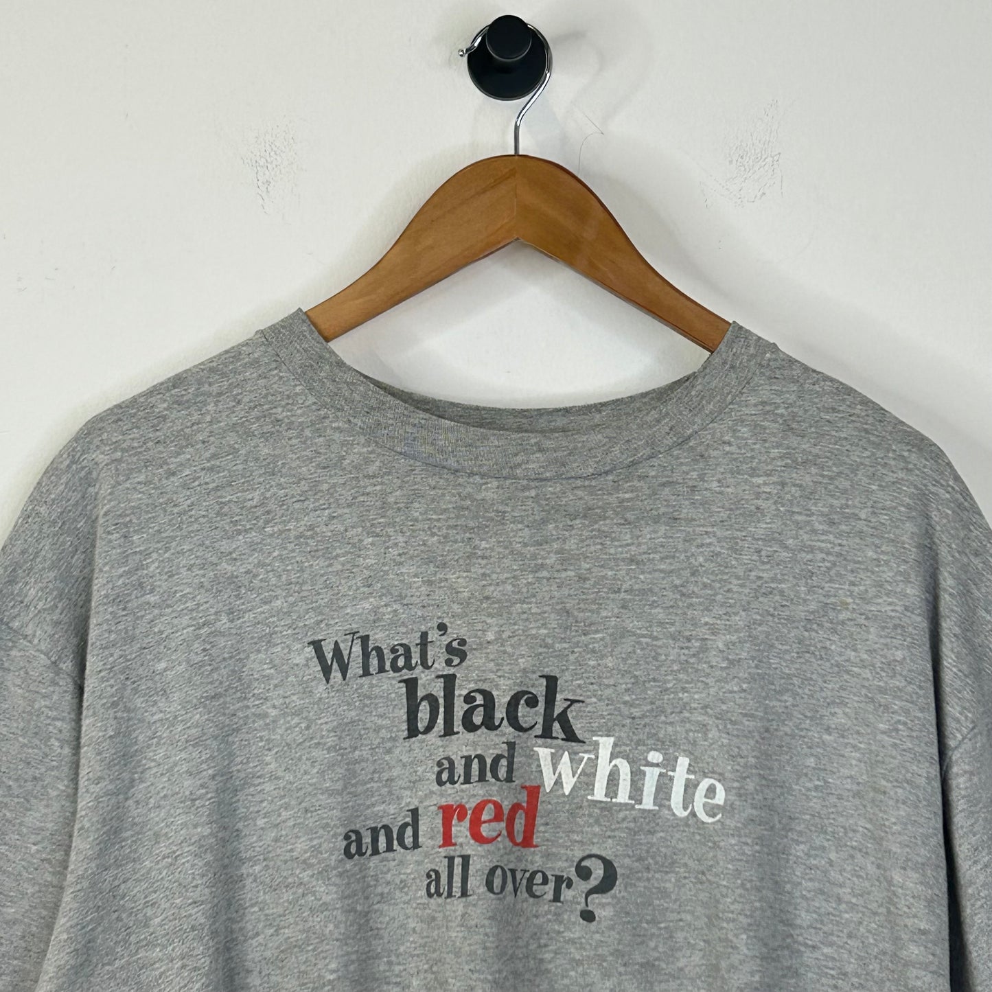 WHATS BLACK WHITE AND RED ALL OVER? TEE